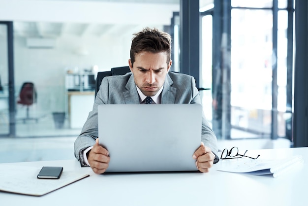 ストレスで眉をひそめ、オフィスのラップトップで怒っている男性、不具合ミスや危機にイライラする不安顔と失敗や問題404または悪いレビュー期限レポートまたは技術的遅延を持つビジネスパーソン