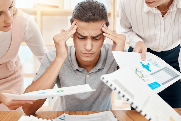 Stress headache and overwhelmed worker with burnout handed office paperwork by manager and employees Mental health anxiety and tired worker stressed or frustrated with note report review deadline