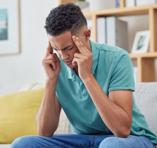 Stress thuis en man op een bank hoofdpijn en burn-out met pijn, vermoeidheid en geestelijke gezondheid Persoon student of man op een bank migraine of uitgeput door angst, gefrustreerd of depressie in een lounge