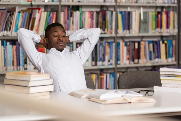 Stressed African Student Of High School Sitting At The Library Desk  Shallow Depth Of Field