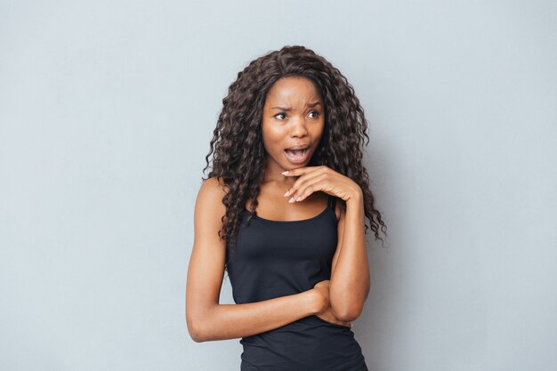 Stressed afro woman screaming on gray wall