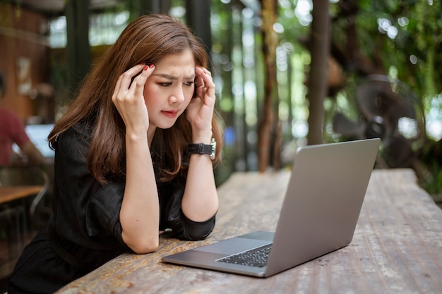 Stressed Asian woman feeling headache in cafe shop