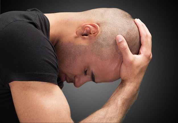 Stressed bald man, hand on head on black background