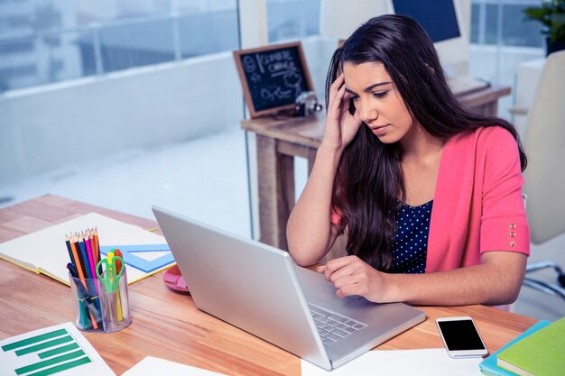 Stressed beautiful businesswoman using laptop while working in creative office