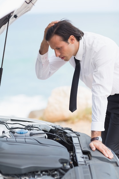 Stressed businessman looking at engine