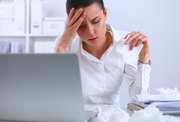 Стрессовая деловая женщина сидит за столом в офисе