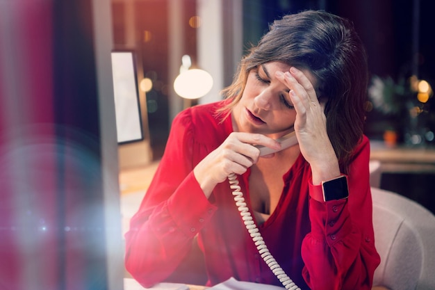 Стрессовая деловая женщина разговаривает по телефону за столом