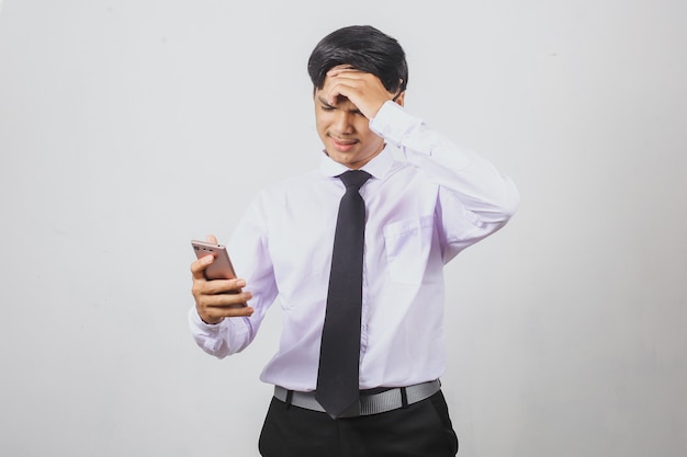 Stressed and confused asian businessman in shirt and tie using smart phone and holding his hea