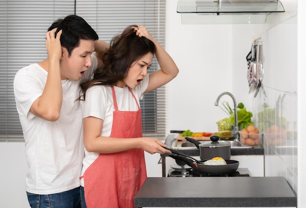 Foto coppia stressata che cucina e prepara il cibo in cucina a casa