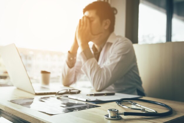 Foto dottore stressato seduto alla scrivania in ufficio