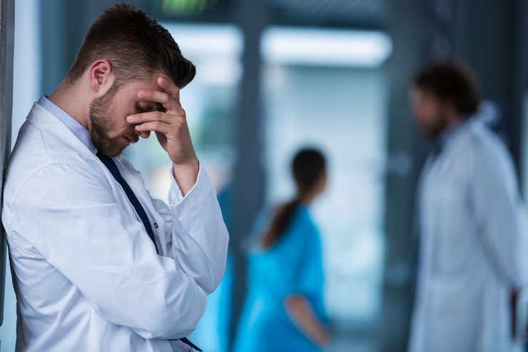 Photo stressed doctor standing against wall in hospital
