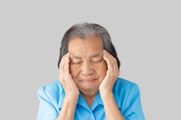 Stressed exhausted grandmother having strong tension headache on a gray background
