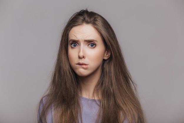 Stressed female bites lip shows dissatisfaction Sorrorful expression negative emotion Isolated on grey background low spirit after quarrel