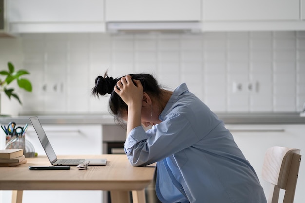 写真 自宅でノートパソコンの前に座ってやる気のないストレスを感じた女性フリーランサー