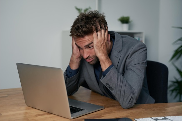 Stressed and frustrated with work Portrait of an overwhelmed businessman sitting at his desk with his face in his hands