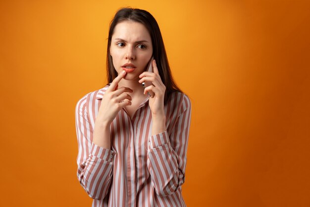 Stressed frustrated young woman holding smartphone recieved bad news yellow background