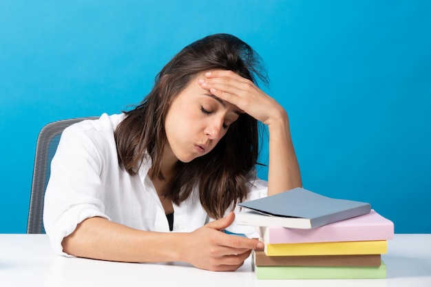 Stressed hispanic student with pile of books