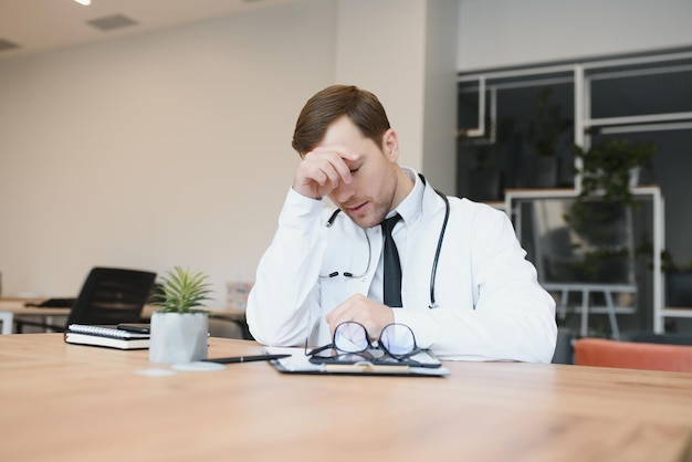 Stressed male doctor Mid adult male doctor working long hours Overworked doctor in his office Not even doctors are exempt from burnout