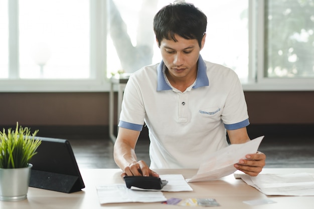 Stressed man calculating credit card debt.