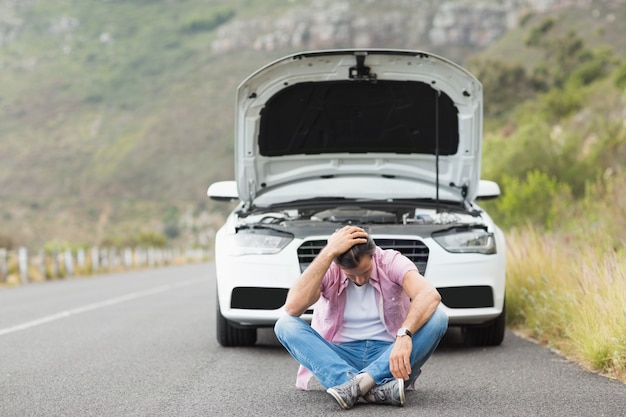 Stressed man sitting after a car breakdown at the side of the road