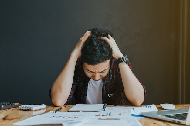 Stressato uomo. un giovane uomo siede alla sua scrivania e tiene le mani