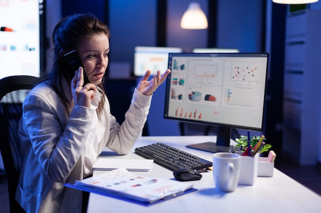 stressed manager talking at smartphone with employee working on financial problems