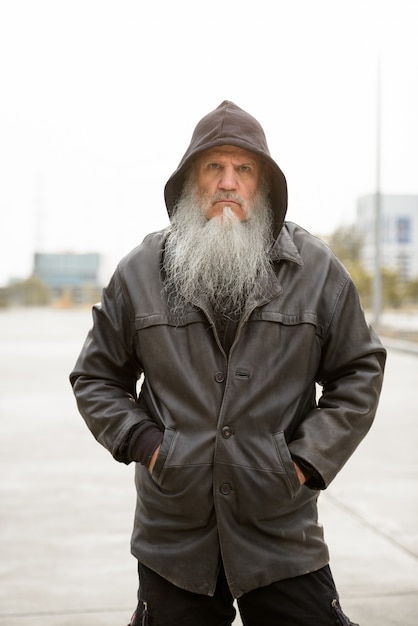 stressed mature bearded hipster man with hood looking serious