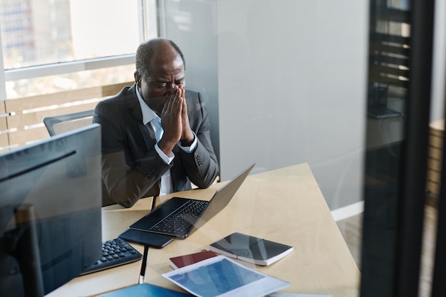 Stressed mature businessman with his hands put together by face