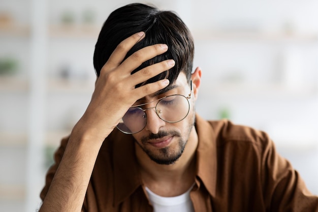 Stressed middle eastern man employee suffering from headache