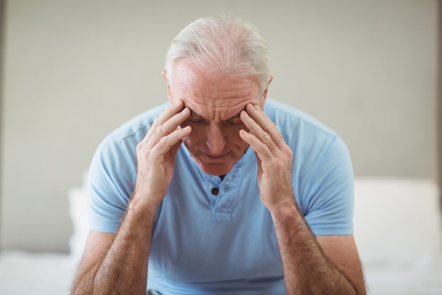 Stressed senior man sitting on bed