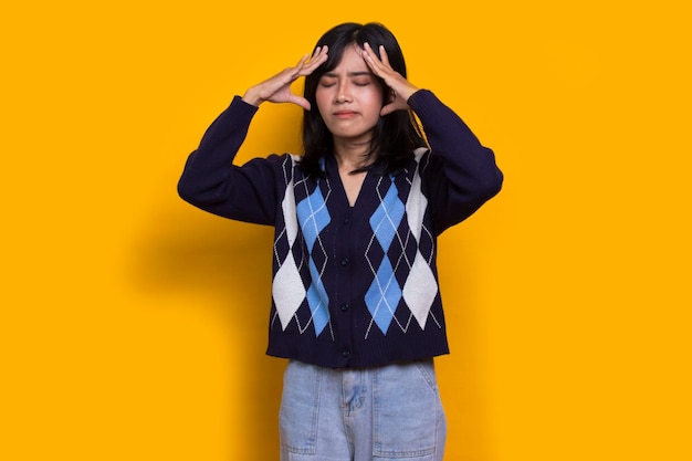 stressed sick asian woman tired with headache isolated on yellow background