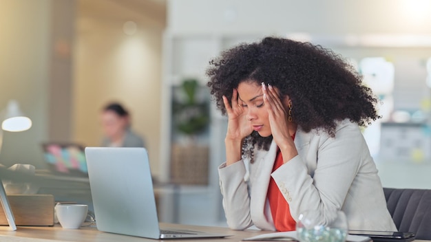 ストレスを抱えたソフトウェアアナリストが頭痛を抱えてノートパソコンに入力し、ビジネスや企業データの分析中にミスをする