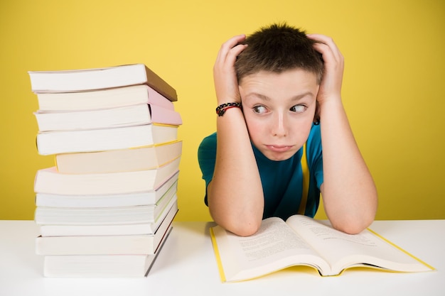 Stressed student boy looking at pile of books