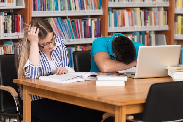 Stressed students in high school sitting at the library desk\
shallow depth of field