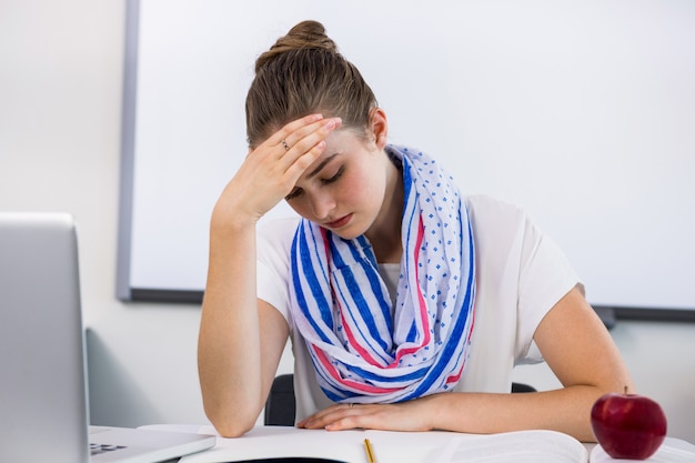 Stressed teacher suffering from headache in classroom