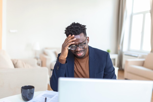 Stressed tired African American man touching temples suffering from headache after long hours work overworked overwhelmed businessman sitting at desk feeling unwell