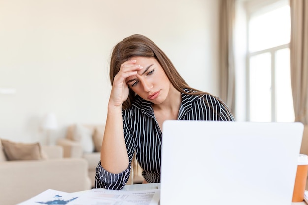 Stressed tired businesswoman feels exhausted sitting at office desk with laptop and crumpled paper frustrated woman can not concentrate having writers block lack of new ideas or creative crisis