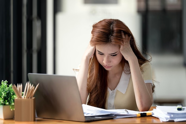 사무실 컴퓨터에서 일하는 스트레스를 받고 있는 젊은 바쁜 아름다운 아시아 비즈니스 여성