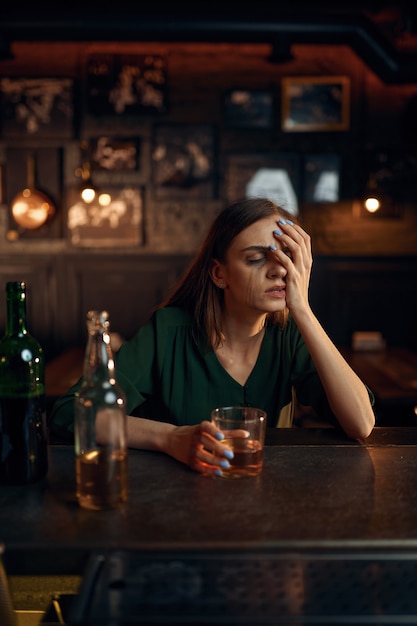 Stressed woman drinks alcohol beverage in bar