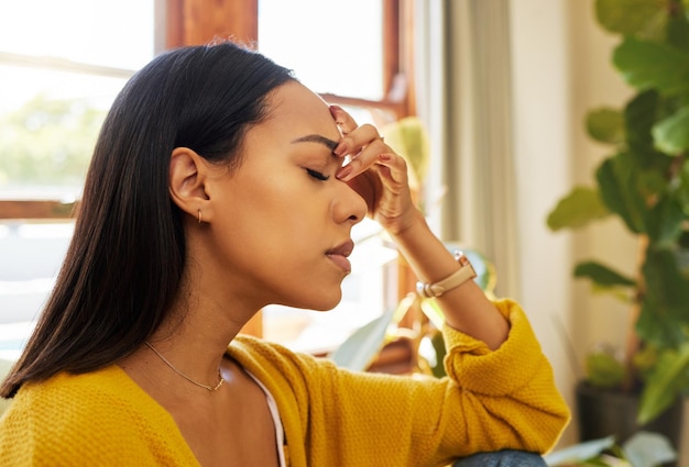 Photo stressed woman headache and burnout with mental health issues at home in the living room female in depression alone holding head feeling anxious depressed and frustrated at the house