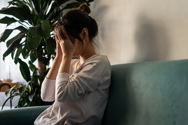 写真 自宅のソファに座っているストレスの多い女性