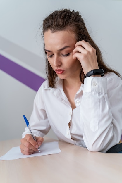 Donna sollecitata che si siede alla tavola. donna oberata di lavoro con documenti.