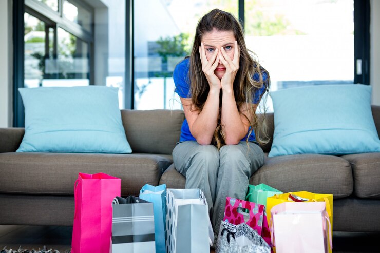 फोटो stressed woman with her head in her hands surrounded by gifts, sitting on a couch