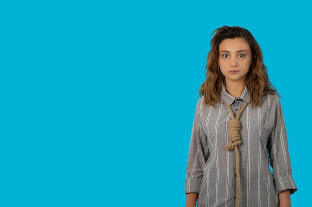 A stressed young adult hang a rope around her neck and looking at camera. High quality photo