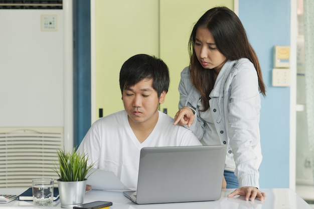 Stressed young asian couple looking at issues notification from bank about late payment home loan credit.