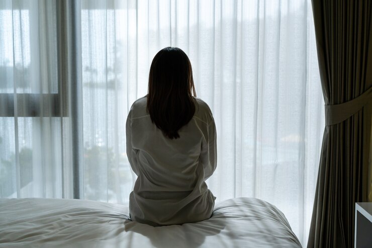 Photo うつ病に苦しんでいて、自宅の暗い寝室に一人で座っている若いアジアの女性を強調しました。