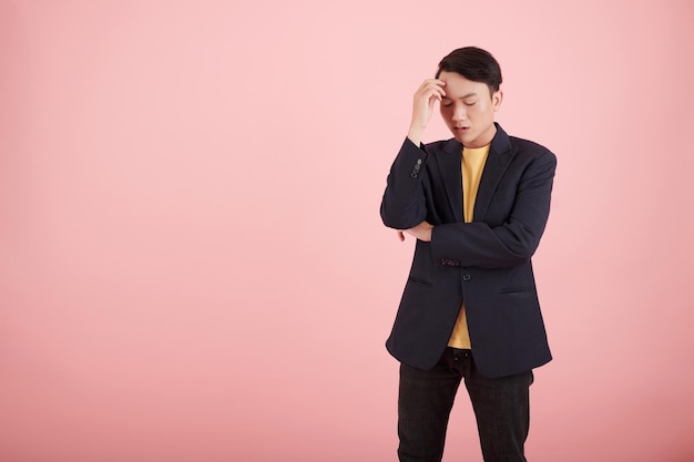 Stressed young businessman thinking how to solve problem isolated on pink