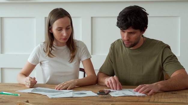 Stressed young couple calculating monthly home expenses, credit card bills payment.