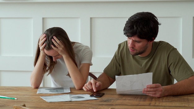 Foto sottolineato giovani coppie che calcolano le spese domestiche mensili, pagamento delle fatture della carta di credito.