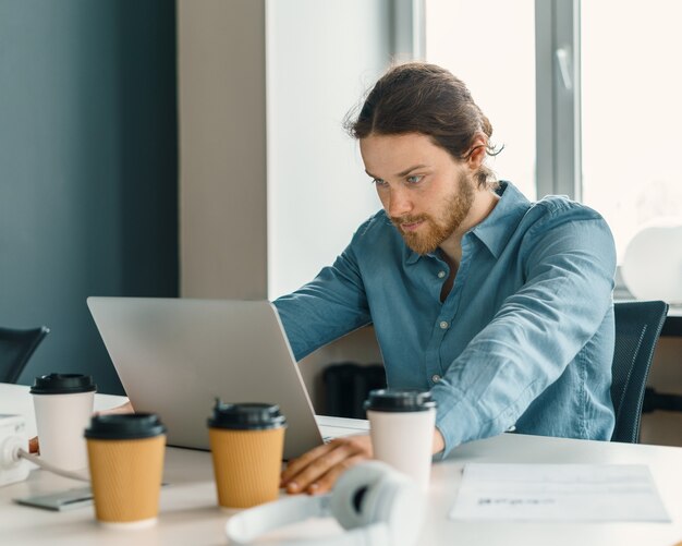 Stressed young male office worker trying to concentrate while working on laptop